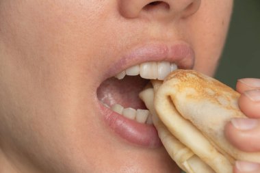 Kızın ağzı gözleme kapağını ısırıyor.