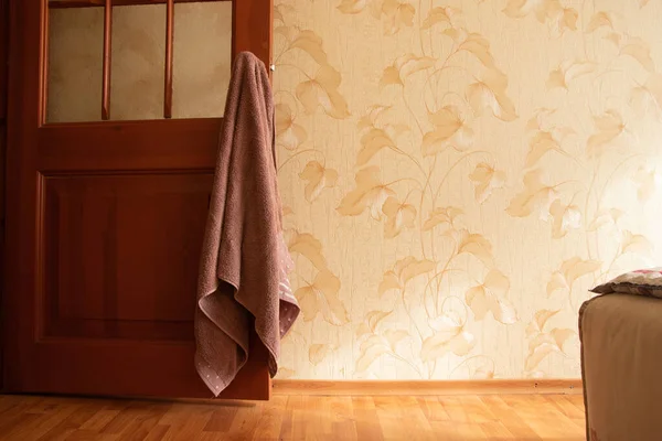 bath towel hanging on the door handle in the bedroom of the house and the light from