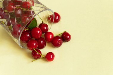 Olgun kirazlar kırmızı arka planda bir bardakta