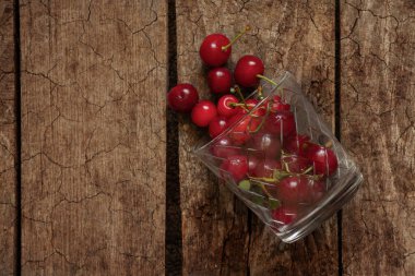 Tahta bir masada, bardakta kiraz.