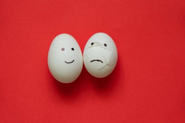 sad and joyful chicken egg on a colored background