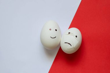 sad and joyful chicken egg on a colored background