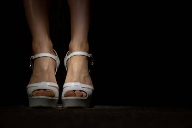 legs of a young girl in white high-heeled sandals on the floor