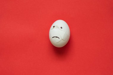 broken sad white chicken egg on a red