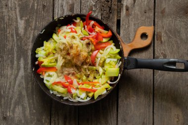 Mutfaktaki ahşap masada kabaklı bir tavada sebze güveci.