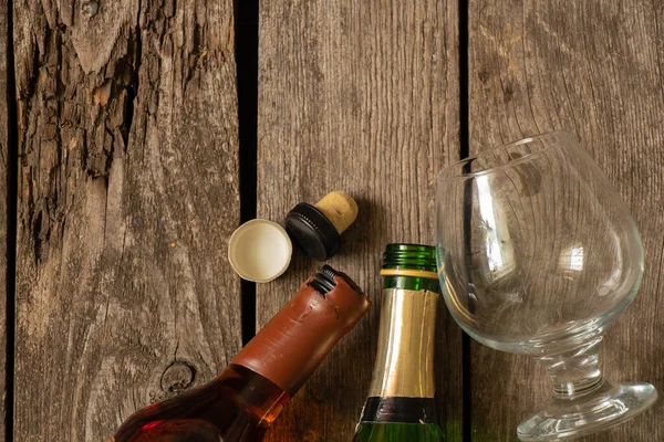 two bottles with wine and whiskey and a glass on a wooden table