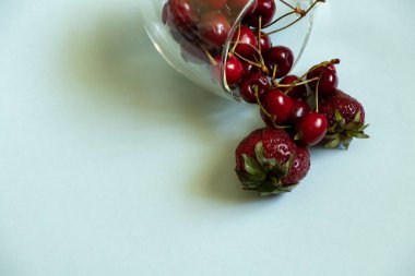 İzole bir zeminde bir fincan olgun çilek.