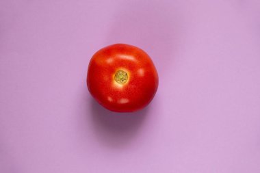 İzole edilmiş mor arkaplanda kırmızı domates. Yakın plan.