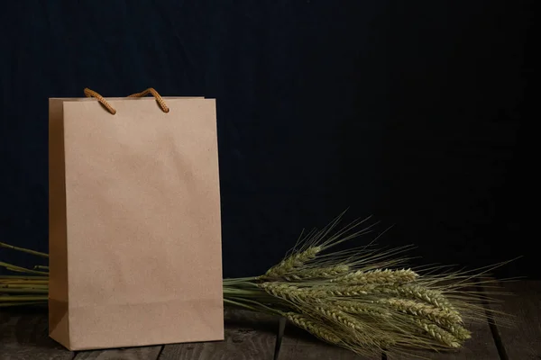 brown paper bag and spikelets of dry wheat on a dark background closeup