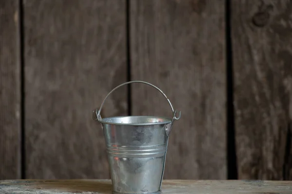 gray metal empty bucket on wooden background closeup