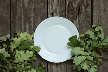 Meşe yaprakları ve ahşap masadaki boş beyaz tabakları temizleyin.