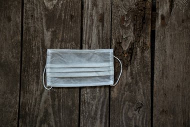 Beyaz tıbbi maske ahşap bir masada yatıyor.