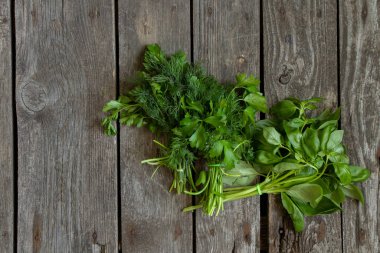 Tahta bir masada taze fesleğen ve maydanoz.