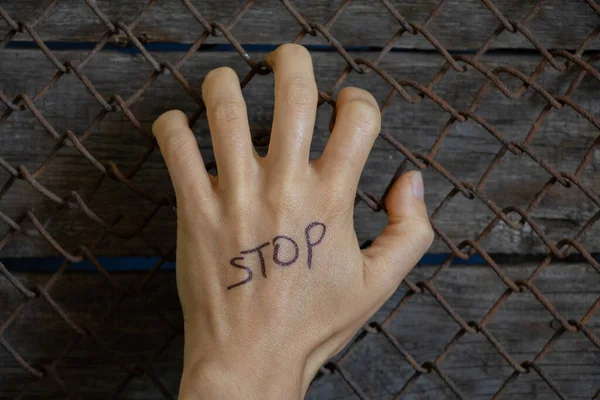 female hand on a grid with the word stop in English, people social problems