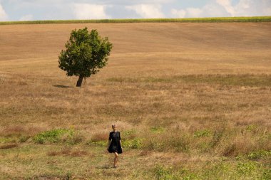 Ağustosta Ukrayna 'da bir kız tarlaya giriyor ve yakınlarda bir ağaç var.