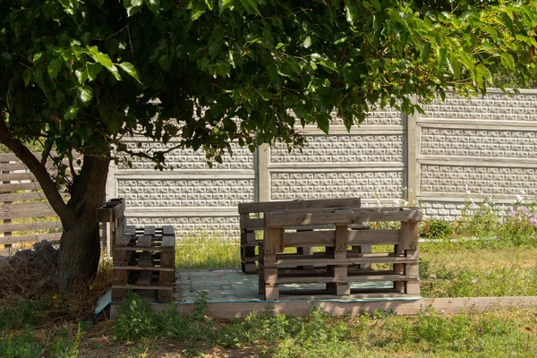 pallet table and chairs stand in the garden under a tree, pallet furniture, manual robot