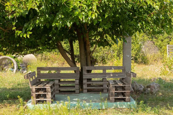 pallet table and chairs stand in the garden under a tree, pallet furniture, manual robot