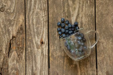 Masanın üzerinde cam şeffaf bardakta dağılmış yaban mersini var.