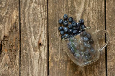 Masanın üzerinde cam şeffaf bardakta dağılmış yaban mersini var.