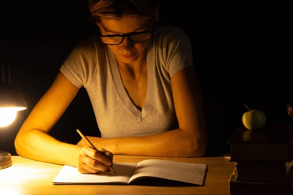 Una Chica Sienta Una Mesa Luz Una Lámpara Cuarto Oscuro —  Fotos de Stock