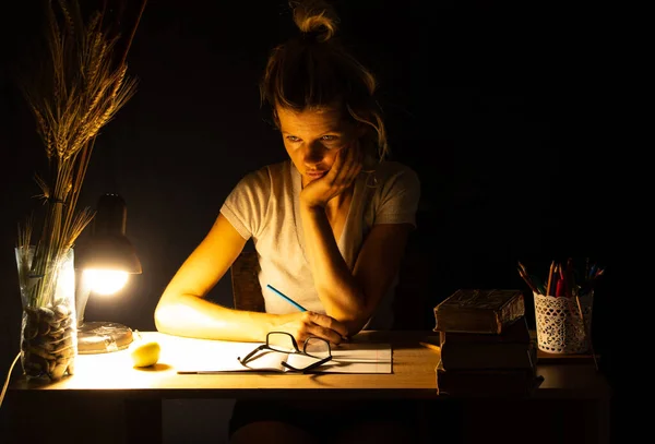 Una Chica Sienta Una Mesa Luz Una Lámpara Cuarto Oscuro —  Fotos de Stock