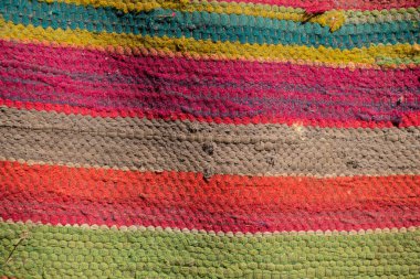 Köydeki büyükannenin arka planı olarak çok renkli eski çizgili bir halı.