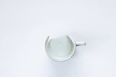 Beyaz arka planda beyaz kırık bardak. Kapat.