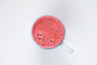 Kahvaltı için fincanda taze sıkılmış kırmızı meyve suyu ve izole edilmiş arka planda köpük.