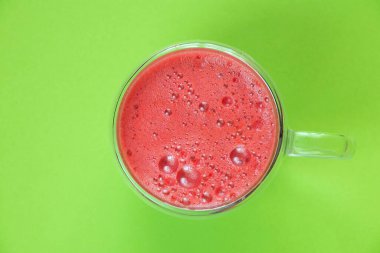 Kahvaltı için fincanda taze sıkılmış kırmızı meyve suyu ve izole edilmiş arka planda köpük.