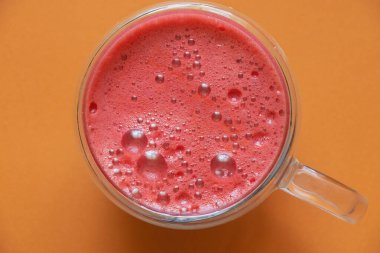 Kahvaltı için fincanda taze sıkılmış kırmızı meyve suyu ve izole edilmiş arka planda köpük.