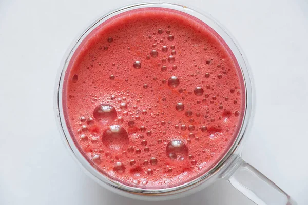 Kahvaltı için fincanda taze sıkılmış kırmızı meyve suyu ve izole edilmiş arka planda köpük.