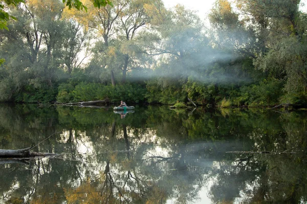 a man on an inflatable boat catches fish on the orel river in ukraine in the forest, fishing on the river