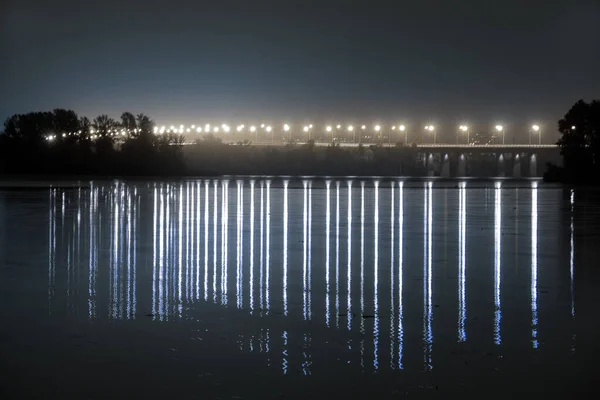 Brücke über den Dnjepr in der Nacht im Licht von Laternenpfählen bei langer Belichtung mit Reflexion auf dem Wasser — Stockfoto