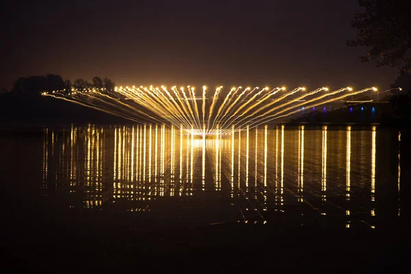 Ponte sobre o rio dnieper à noite nas luzes dos postes de iluminação em longa exposição com reflexão sobre a água — Fotografia de Stock