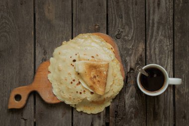 Tahta bir masada bir yığın kızarmış krep ve kahvaltıda kahveli bir fincan.