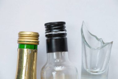 Kırık cam ve boş bir şişe alkollü içecek beyaz arka planda, alkol bağımlılığı