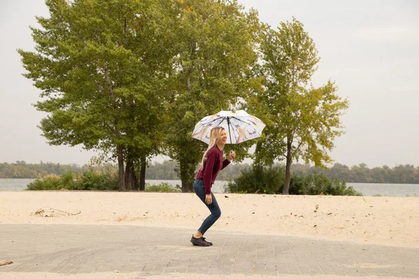 girl with an umbrella jumping into parks in a strong wind in Ukraine in the fall, not the weather, strong wind in the fall