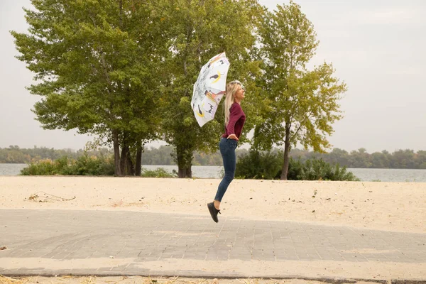 秋のウクライナの強風で公園に飛び込む傘を持つ女の子天気ではなく 秋の強い風 — ストック写真