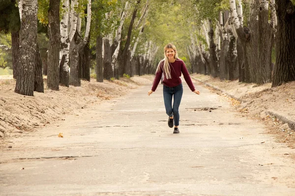 女の子がウクライナの秋の公園の道路を走っていて — ストック写真