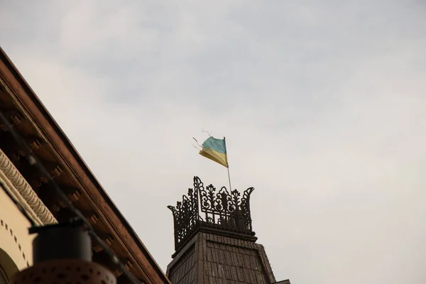 Torn flag of ukraine yellow-blue on the roofs of a house in the center of dnipro city in ukraine — Stock Photo, Image