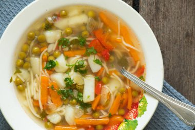 Mutfaktaki masada beyaz tabakta ev yapımı sebze çorbası, etsiz çorba.
