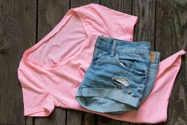 粉红女人T恤平底裤躺在乡村褐色的背景上 女人的衣服 — 图库照片