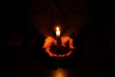 Yaşlı kadının elleri ve karanlıkta mum alevi, mum ışığı, yas, karanlıkta mum.