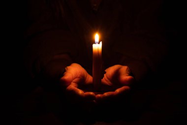 Yaşlı kadının elleri ve karanlıkta mum alevi, mum ışığı, yas, karanlıkta mum.