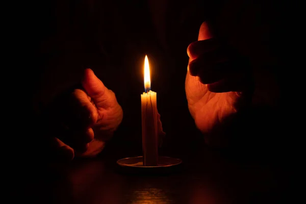 old woman\'s hands and candle flame in the dark, candle light, mourning, candle in the dark