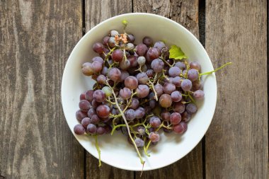 Mavi üzümler mutfaktaki bir tabakta masanın üzerinde yatıyor.
