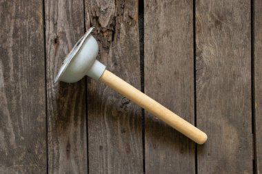 Ahşap arka planda boru temizliği için tahta saplı tuvalet lastiği.