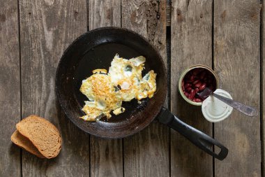 Sabah çırpılmış yumurta ve fasulye. Mutfaktaki ahşap masada.