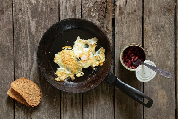 Sabah çırpılmış yumurta ve fasulye. Mutfaktaki ahşap masada.