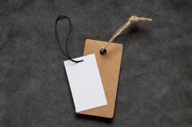 Kahverengi boş bir etiket ve ipte beyaz bir tane yakın plan tasarım için gri tüylü bir kumaşın üzerinde duruyor.